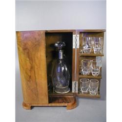 An Art Deco walnut veneered drinks wardrobe with interior fitted for two decanters and twelve tum...