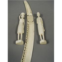 A pair of carved ivory African figures and a large tusk size carving, decorated with graduated el...