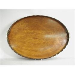 A George III oval mahogany tray with a wavy border and brass handles, 70cm long Est. 300/350...