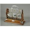 Image 1 : An Edwardian three bottle tantalus, each with plated decanter labels; brandy, sherry and whiskey,...