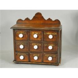 A 19th century spice chest with an arrangement of nine drawers, each named, with white bun handle...