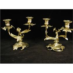 A pair of early 20th century ormolu candelabra, each with twin sconces on scrolling leaf branches...