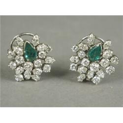 A pair of emerald and diamond cluster earrings each set with a central pear shape emerald and pea...