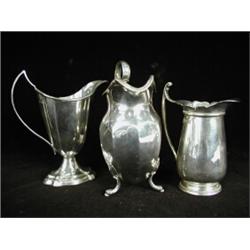 A George V silver cream jug, Birmingham 1930, 13cm high, another cream, Sheffield 1903, and one o...
