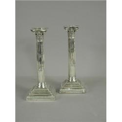 A pair of weighted silver candlesticks with stop fluted columns and stepped bases, with presentat...