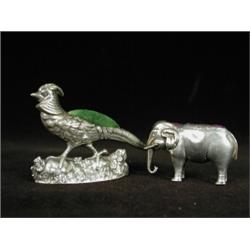Two silver pin cushions: one in the form of an elephant 1910, 4cm long and one in the form of a g...