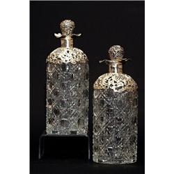 A pair of late Victorian pressed clear glass cylindrical decanters, with silver mounted stoppers,