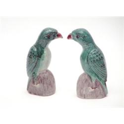 A pair of Kang Hsi famille verte biscuit porcelain figures of parrots, standing on aubergine glaz...