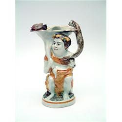 An early 19th century Prattware bacchus jug, with catfish head spout and otter handle with 2 figu...