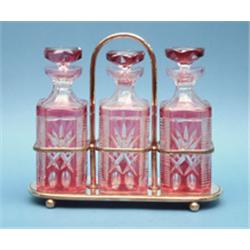 A plated tantalus, fitted with 3 ruby overlaid glass decanters £300-400...