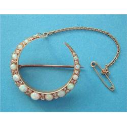 A 15ct gold crescent brooch, set thirteen round opals spaced by pair of diamonds £700-1,000...