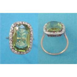 A gold dress ring, claw set with an oval faceted peridot, in a border of diamonds (peridot approx...