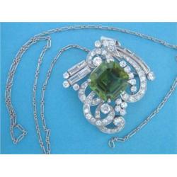 A white gold diamond and peridot brooch/pendant, of stylised scroll design, set brilliant and bag...