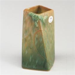 ROSEVILLE Futura twisted four-sided vase with branches and leaves on a mottled orange to green gr...