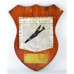 Wooden plaque with a piece of tail fan, and a brass