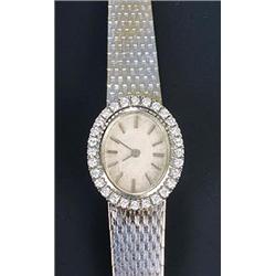 A Swiss lady's diamond oval bracelet watch, circa 1960, the textured silvered dial with baton num...