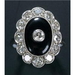 An early 20th century black onyx and diamond oval cluster ring, the central oval black onyx panel...