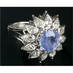 A sapphire and diamond flower-head cluster ring, centred with a cushion-shaped native-cut sapphir...