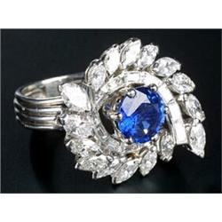 A modern French platinum sapphire and diamond cluster ring, centred with a round mixed-cut sapphi...