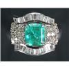 Image 1 : An emerald and diamond shaped-oblong cluster ring, centred with a trap-cut emerald within a surro...