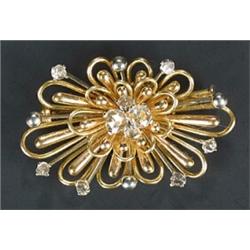 A modern rose diamond brooch in the form of a bi-colour stylised open work flower-head with diamo...