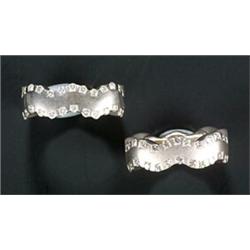 A pair of matching diamond rings, each square white band with wavy edges set with 26 small round...