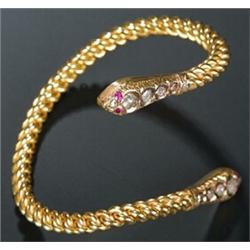 A modern Middle Eastern ruby and diamond curb link torque bangle with serpent terminals set with...