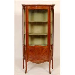 A French Vitrine, of serpentine form, the marble top above a glazed and paneled door, with kingwo...
