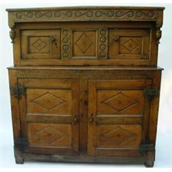 An early 18th century oak press cupboard having carved cornice over recessed cupboard enclosed by...