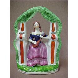 Staffordshire figurine of woman seated under trellis, 9 1/2" high, mid 19th C., (hairline crack o...