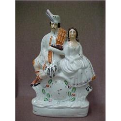 Staffordshire double figurine, seated man in kilt and seated woman, over clock, (crack on back),...