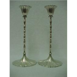 A pair of sterling silver weighted candlesticks, fluted candleholders over leaf shaped decoration...