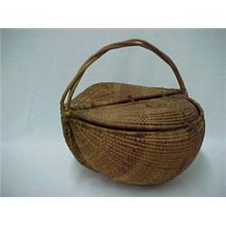 American woven basket in round form with D shaped hinged lid, C shaped twig handle, basket is wov...