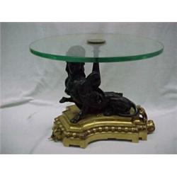 Round glass top table with bronze figure of a sphinx on gilt metal base, 20th C. Estimate 800/...