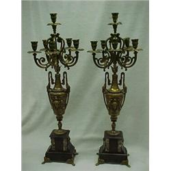 A pair of spelter candelabrum, each with six candleholders on urns, standing on rectangular slate...