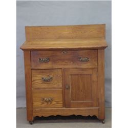Oak washstand with backsplash, large single drawer over single door and two small drawers.