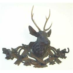 An early 20th century Swiss hat rack carved with a stag's head and set with real antlers, on rust...