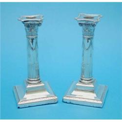 A pair of George V silver corinthian column candlesticks with beaded sconces and loaded feet, mar...