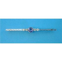 An Edwardian white gold bar brooch, millegrain set with a central sapphire and four diamonds...