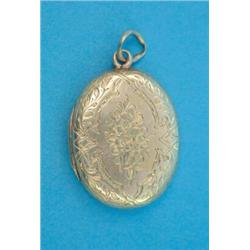 A gold foliate engraved oval pendant locket...