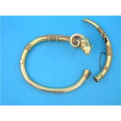A Victorian Etruscan design gold hinged bangle, with rams head terminal (a.f)...