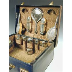 An Edwardian ladies green leather travel toiletry set comprising six silver topped bottles, two s...