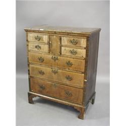 An 18th century walnut chest of four small drawers with a central cupboard, over three long drawe...