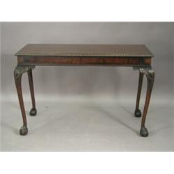 A Chippendale style mahogany serving table with a gadrooned border and scrolled legs with carved...
