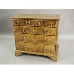 A walnut chest of two short and three long drawers with feather banding on bracket feet, basicall...