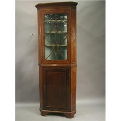 An Edwardian inlaid corner cupboard, the top section with a glazed door, over an inlaid lower sec...
