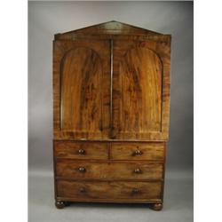 An early Victorian mahogany linen press with an architectural cornice over two panelled doors and...