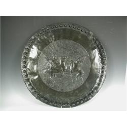 An Arts & Crafts copper charger, the centre with a mounted Norseman slaying a dragon, 58cm dia...