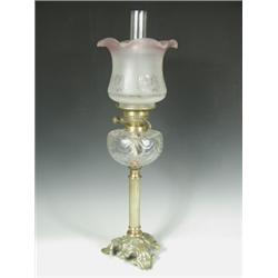 A Victorian oil lamp, with a tinted shade above a moulded glass reservoir supported upon a bra...