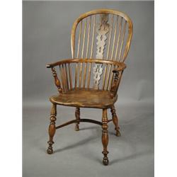 An early 19th century yewwood Windsor armchair, with a pierced splat, over a crinoline stretch...